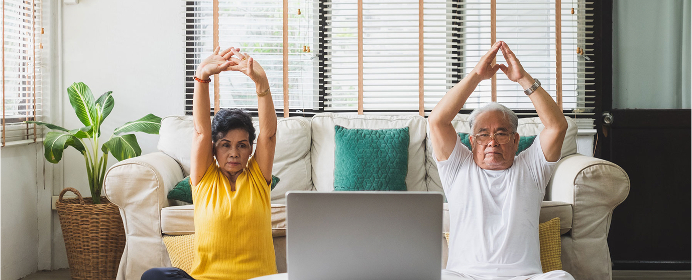 A woman and a man sit on the floor doing yoga.