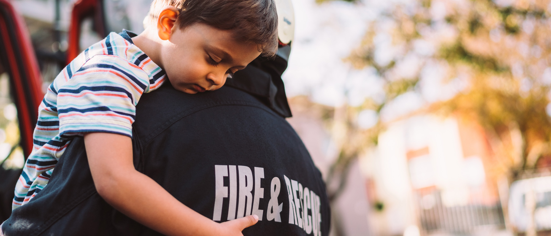 A firefighter holds a child in their arms.