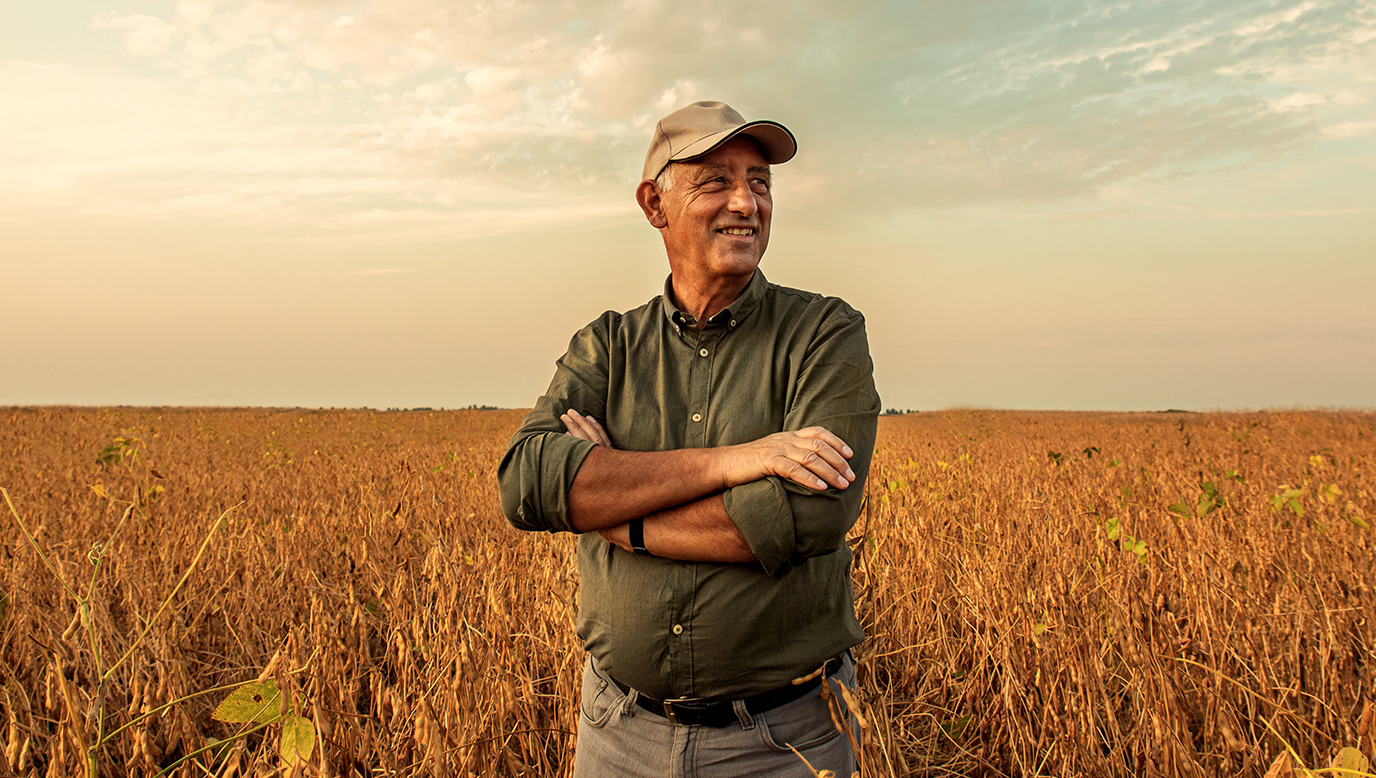 A farmer stands in a field of wheat.