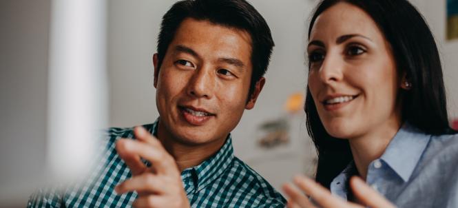 A man and woman point at a computer screen.