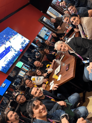 A large group of Bixal team members sit around a table in a bar.